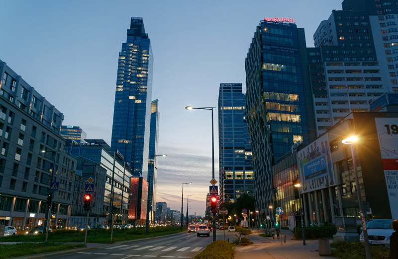 1 - A bustling street scene in Warsaw, Poland, featuring modern high-rise buildings and intense evening traffic
